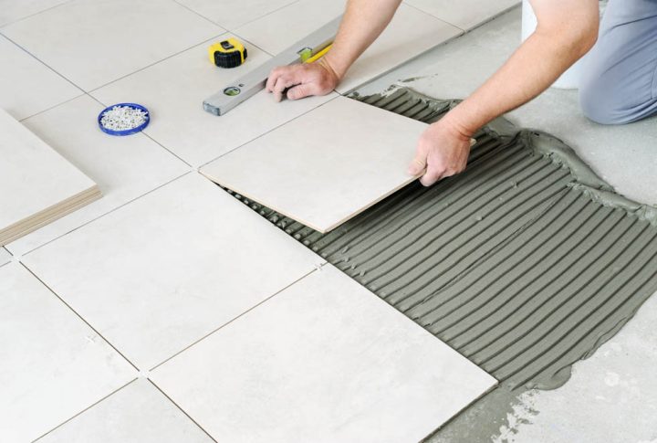 worker laying the ceramic tile on the floor